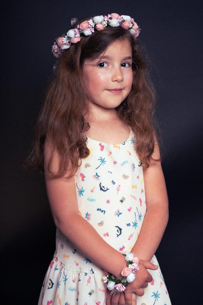 Petite fille pendant un shooting studio avec une couronne de fleur sur la tête sur fond noir