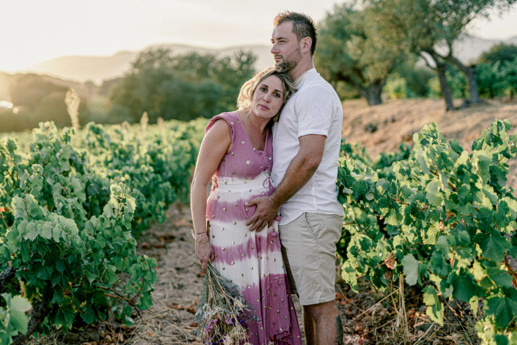 couple avec femme enceinte avec robe coloré au milieu des vignes