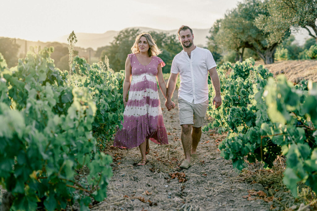 couple avec femme enceinte avec robe coloré marchant au milieu des vignes