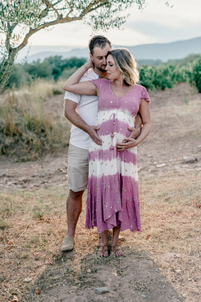 Couple avec femme enceinte avec robe colorée à côté d'un olivier.