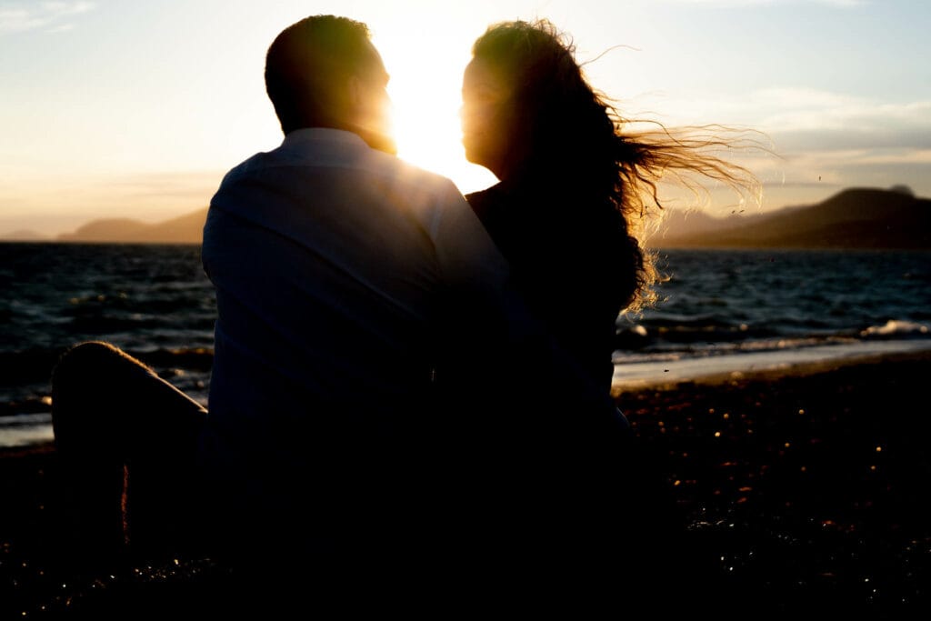 Couple assis sur la plage en ombre chinoise cheveux au vent